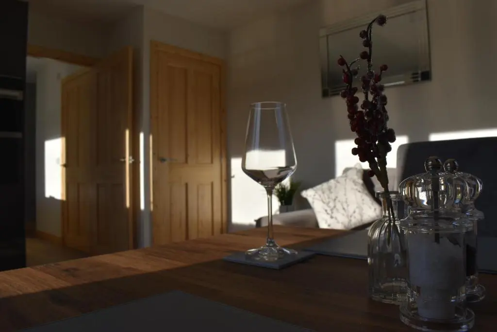 a table with a wine glass and a vase with flowers at Grantown Caravan Park in Grantown on Spey
