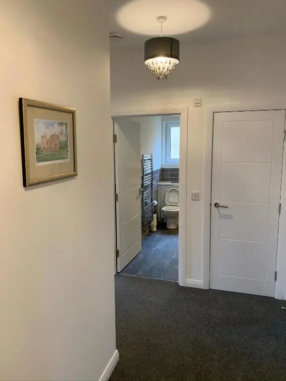 a hallway with a bathroom with a toilet and a chandelier at Atholl Place View in Inverness