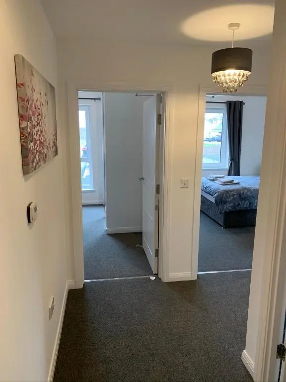 a hallway with a bedroom and a bed and a chandelier at Atholl Place View in Inverness