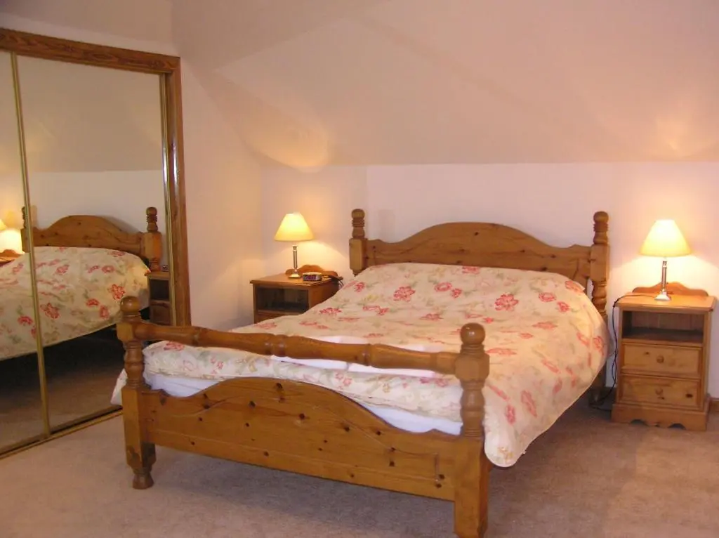 a bedroom with a bed and a mirror at The Antlers in Lybster