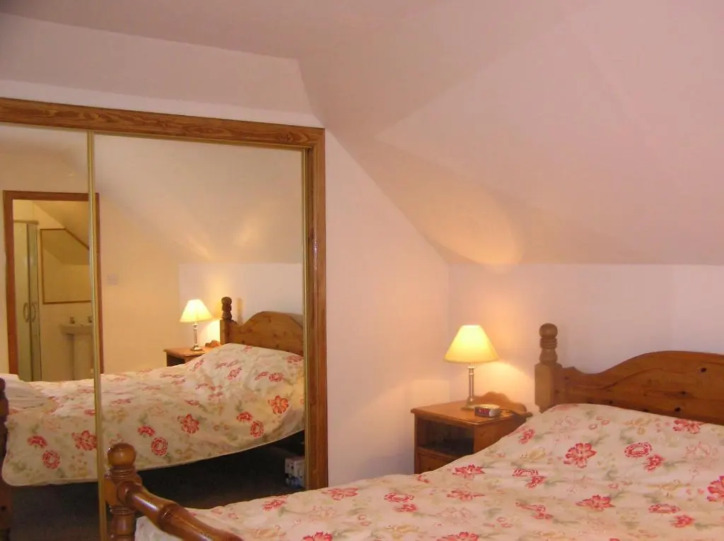 a bedroom with two beds and a mirror at The Antlers in Lybster