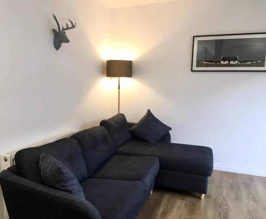 a living room with a blue couch and a lamp at The Tack Room in Inverness