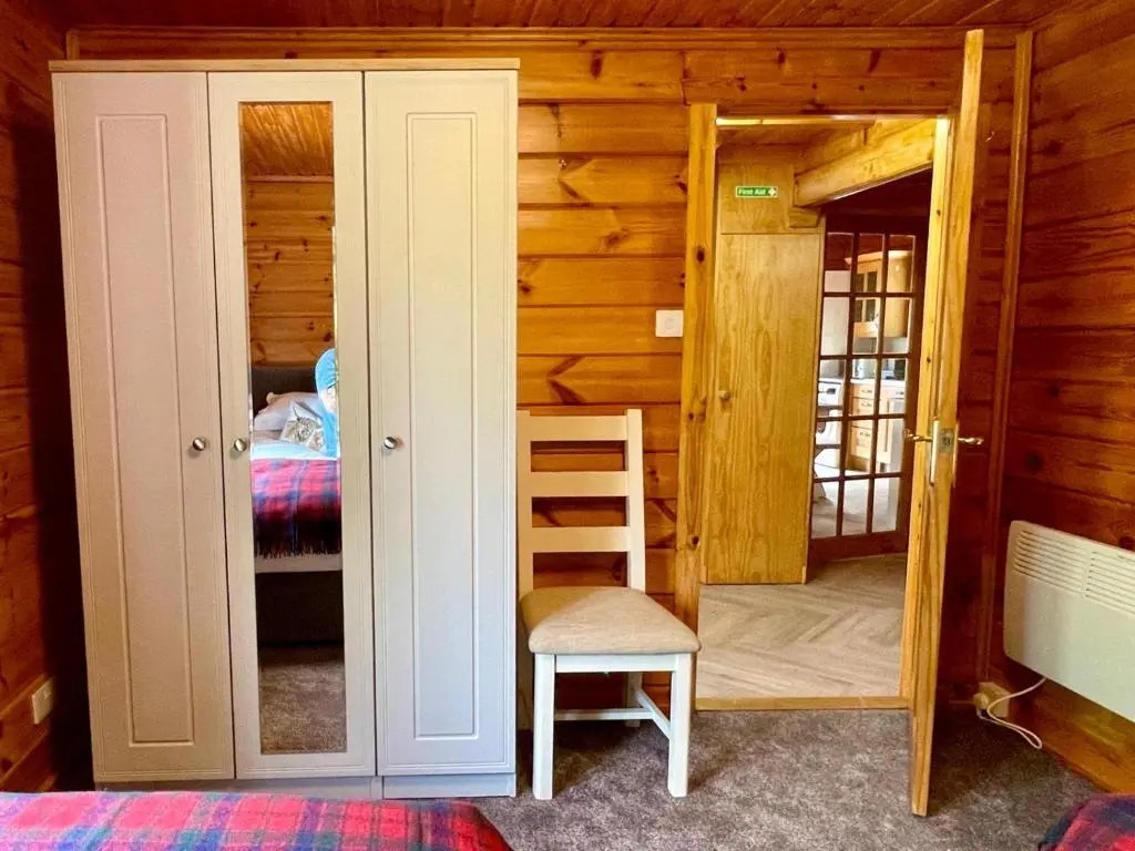 a bedroom with a door and a chair and a bed at Deveron Valley Cottages in Marnoch