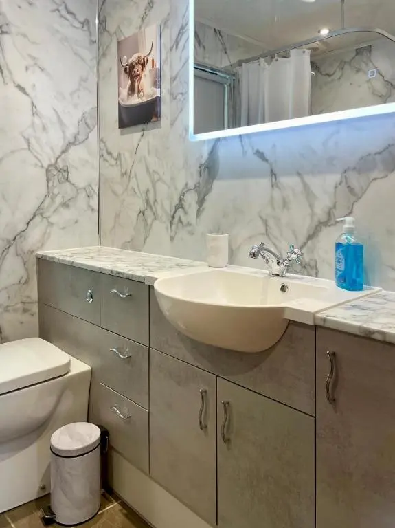 a bathroom with a sink and a toilet and a mirror at Deveron Valley Cottages in Marnoch