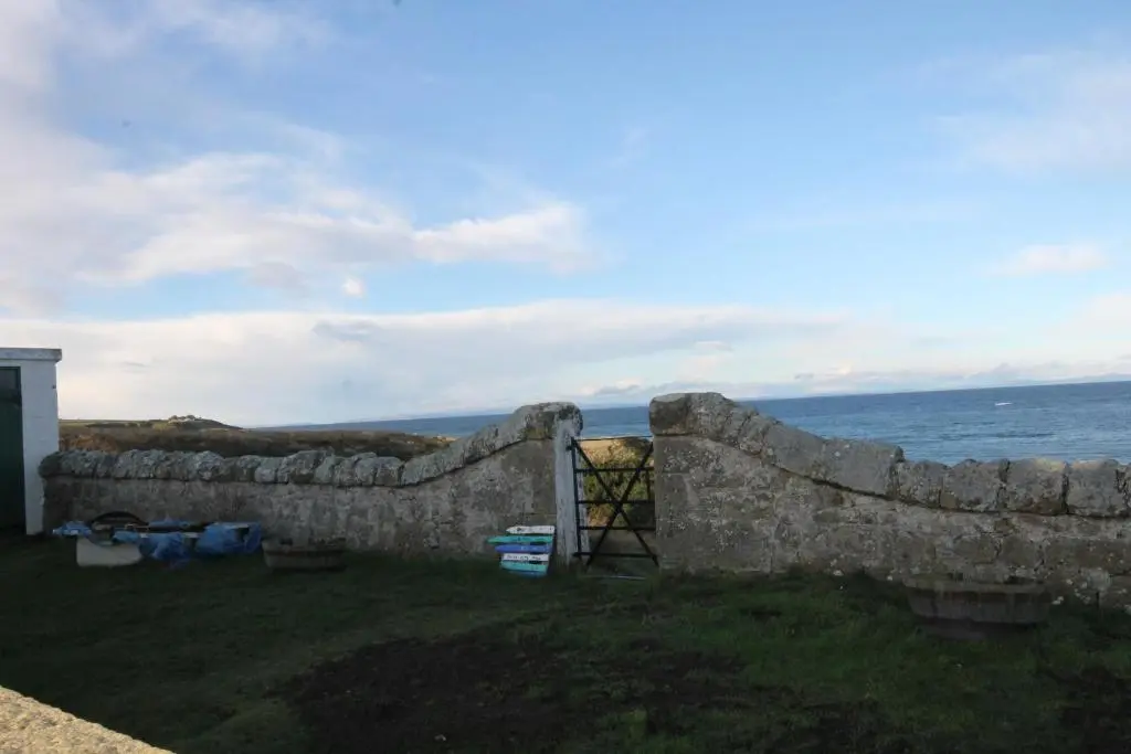 a stone wall with the ocean in the background at Covesea Lighthouse Cottages in Lossiemouth