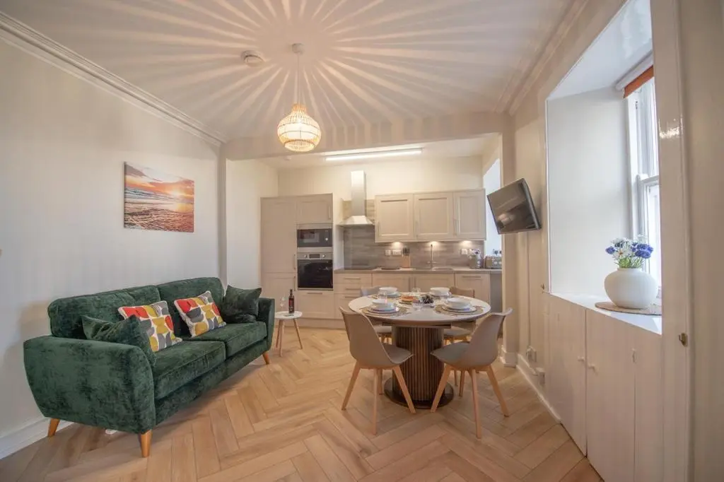 a living room with a green couch and a table at Covesea Lighthouse Cottages in Lossiemouth