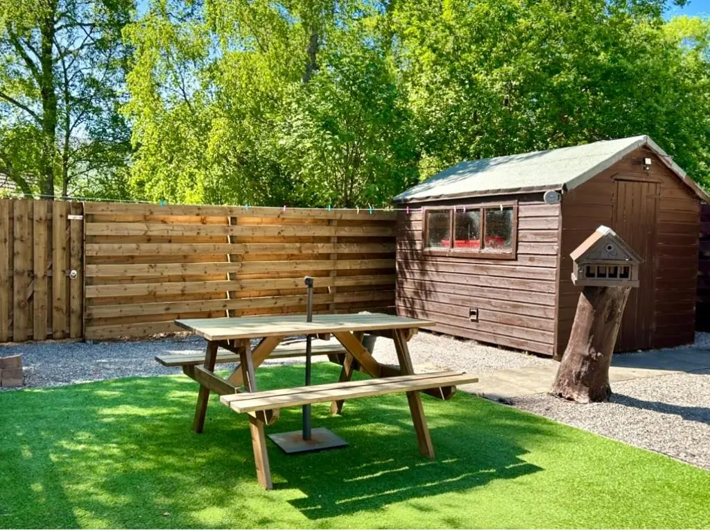 a picnic table and a bird house next to a fence at Rendezvous , Aviemore in Aviemore