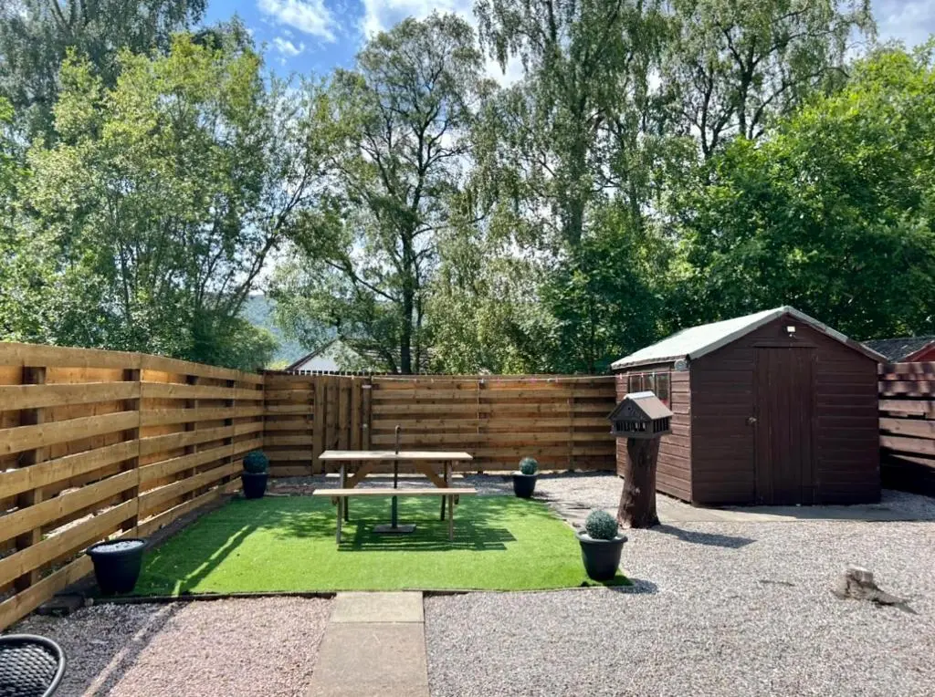 a backyard with a picnic table and a fence at Rendezvous , Aviemore in Aviemore