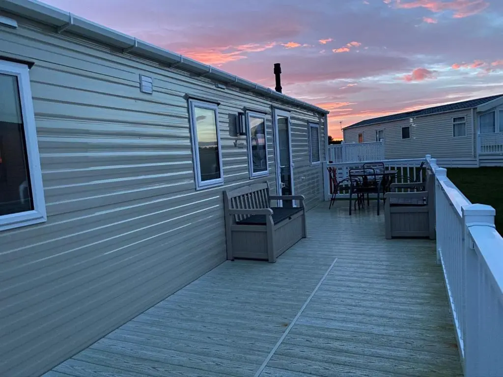 a deck with chairs and tables on the side of a building at Paul\u2019s place silversands in Lossiemouth