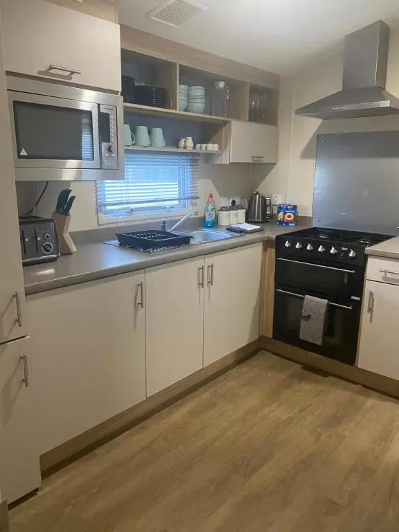 a kitchen with white cabinets and a black stove top oven at Paul\u2019s place silversands in Lossiemouth