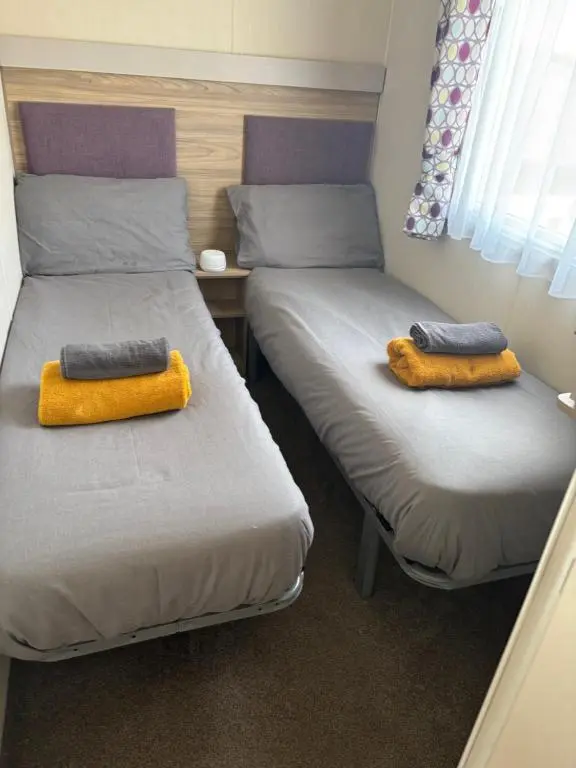 two beds in a room with yellow pillows on them at Paul\u2019s place silversands in Lossiemouth