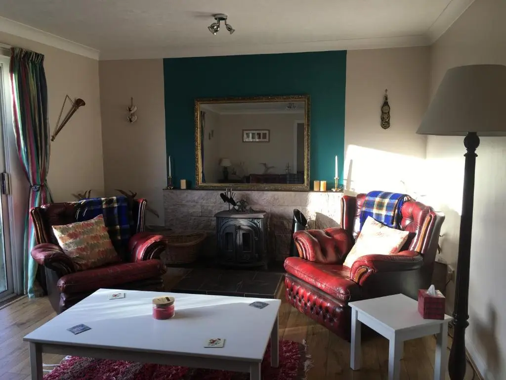 a living room with two chairs and a fire place at Unique Garden Centre Country Cottage in Fraserburgh