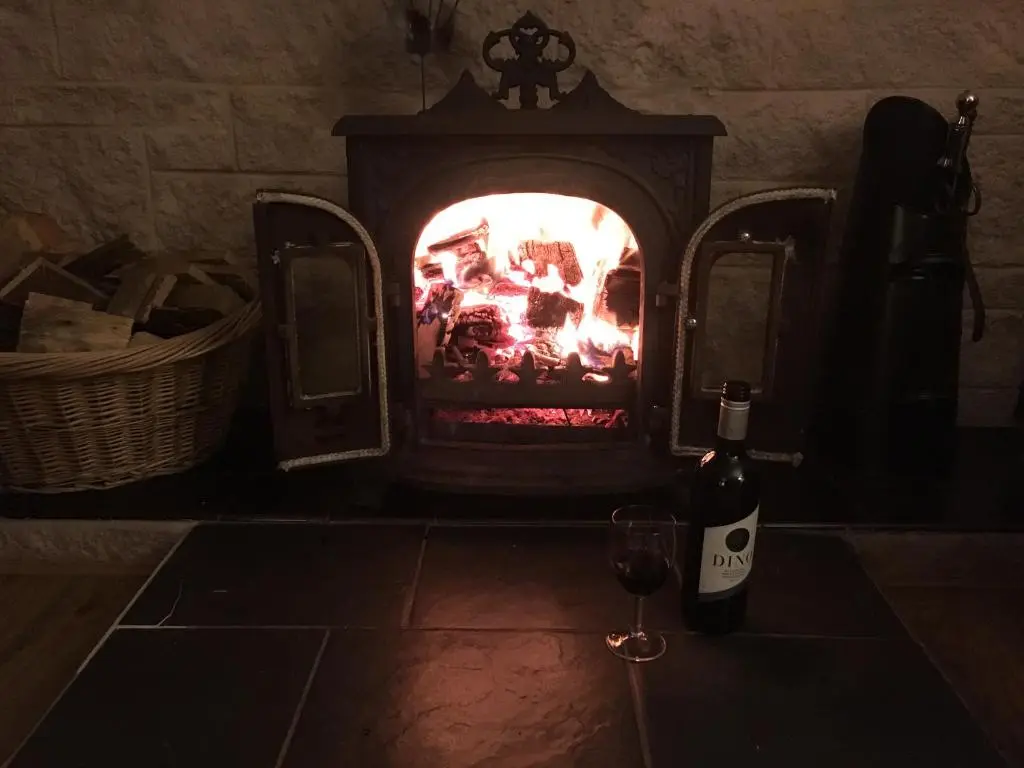 a bottle of wine and a glass in front of a fireplace at Unique Garden Centre Country Cottage in Fraserburgh