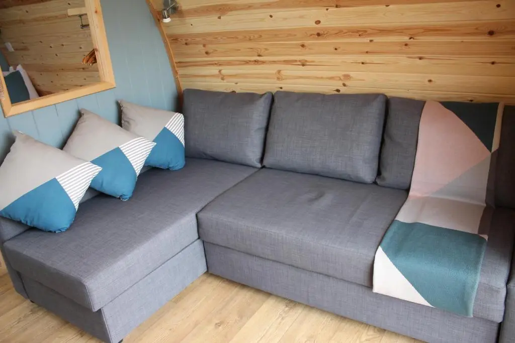 a gray couch with pillows in a room at North Star Glamping in Lybster