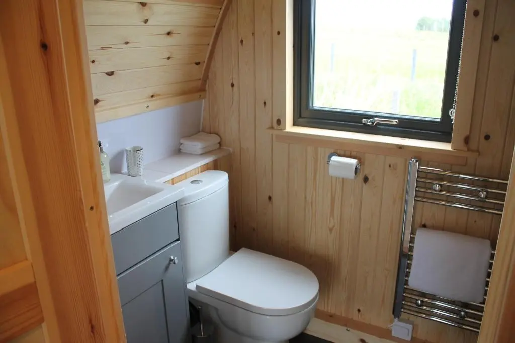 a bathroom with a toilet and a sink and a window at North Star Glamping in Lybster
