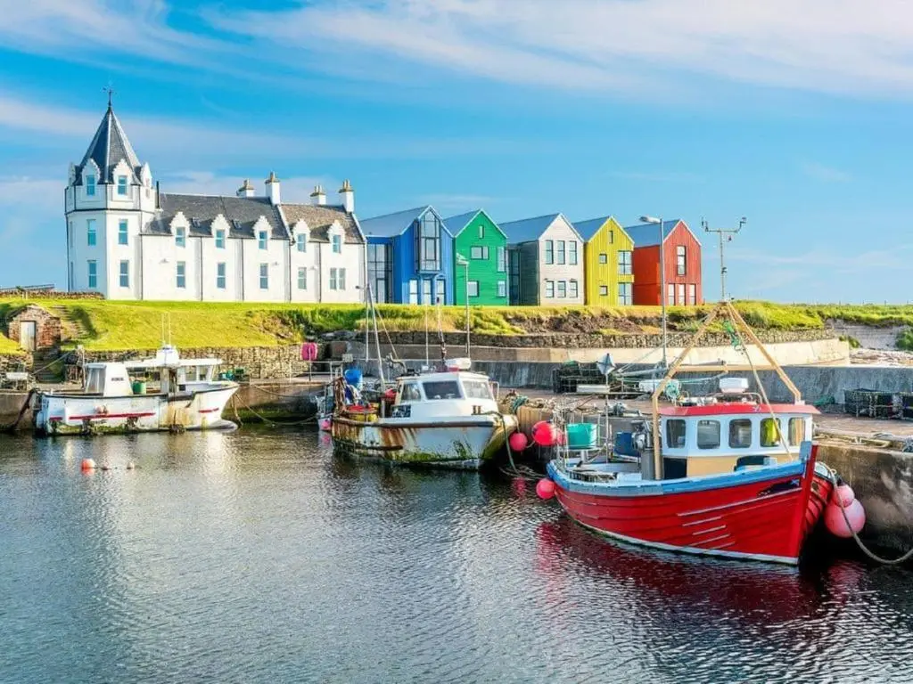 a group of boats in the water in front of a building at North Star Glamping in Lybster