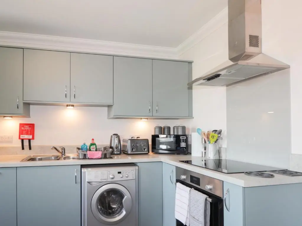 a kitchen with white cabinets and a dishwasher at The Nook in Inverness
