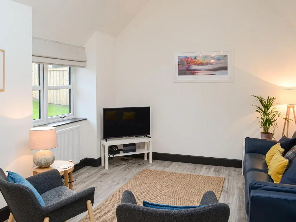 a living room with a couch and a tv at Mile End Cottage in Inverness