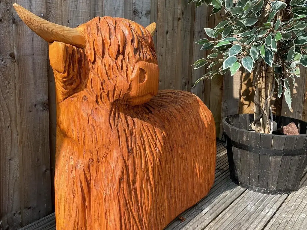 a wooden bear statue sitting next to a plant at Mile End Cottage in Inverness