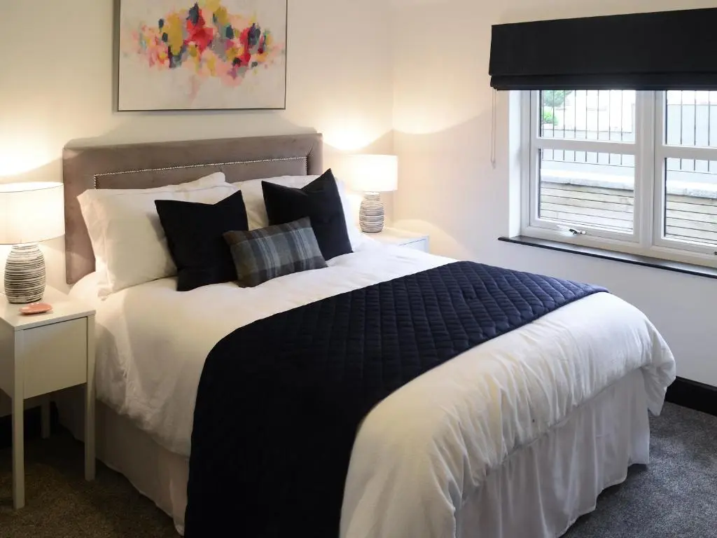 a bedroom with a black and white bed and a window at Mile End Cottage in Inverness
