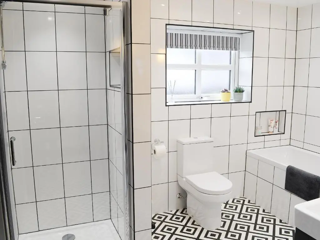a white bathroom with a toilet and a window at Mile End Cottage in Inverness