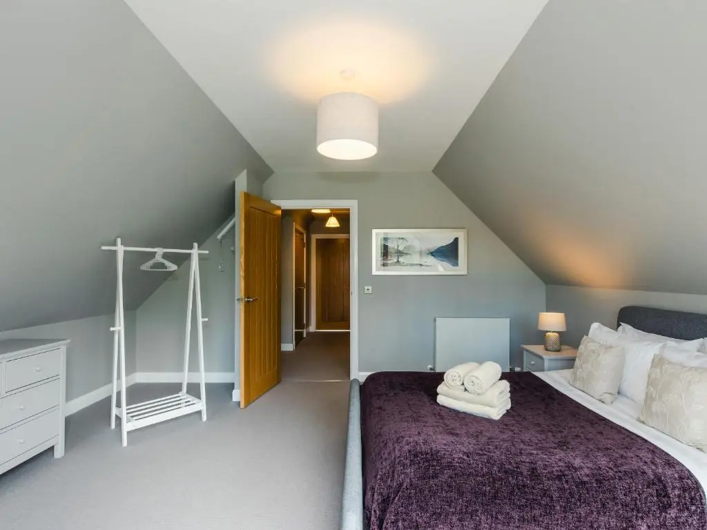 a bedroom with a large bed with a purple blanket at Otter Lodge in Kingussie