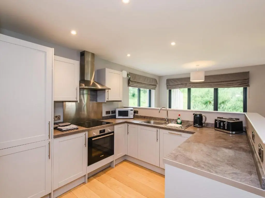 a large kitchen with white cabinets and appliances at Otter Lodge in Kingussie