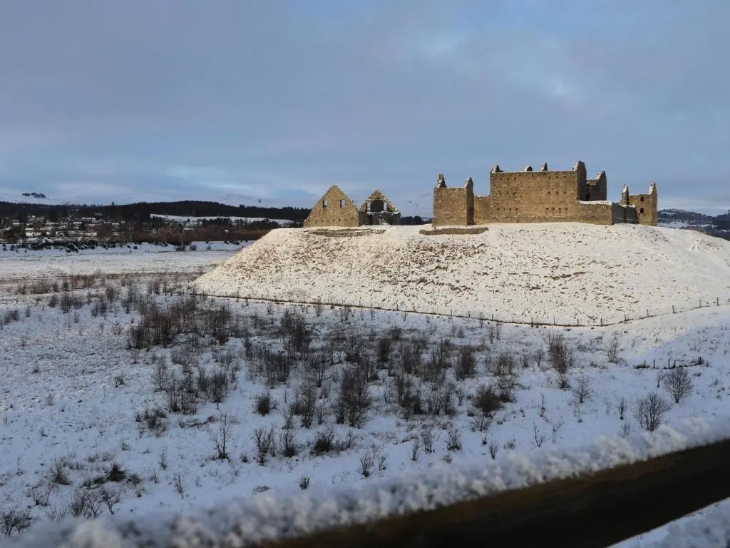 an old castle in the middle of a snow covered field at Otter Lodge in Kingussie