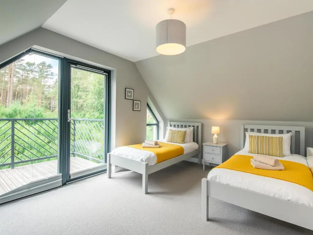 two beds in a room with a balcony at Golden Eagle Lodge in Kingussie