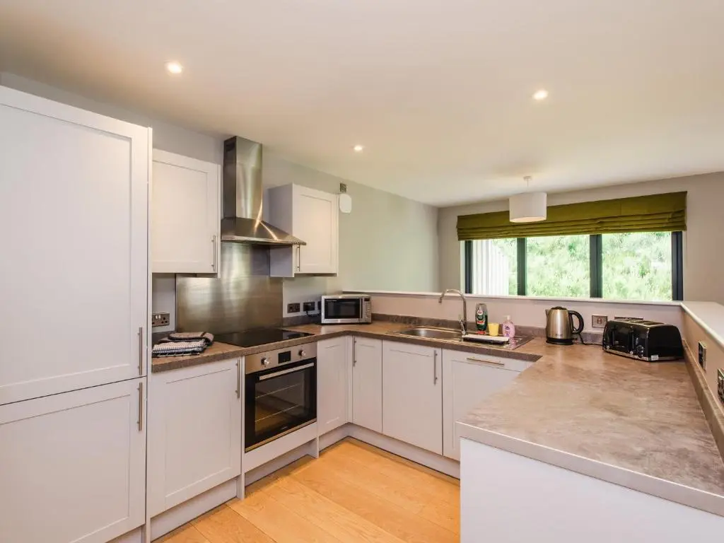 a large kitchen with white cabinets and appliances at Golden Eagle Lodge in Kingussie