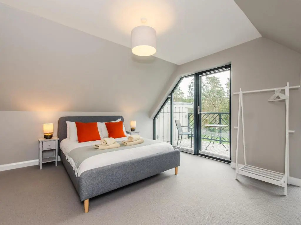 a bedroom with a bed and a large window at Red Deer Lodge in Kingussie