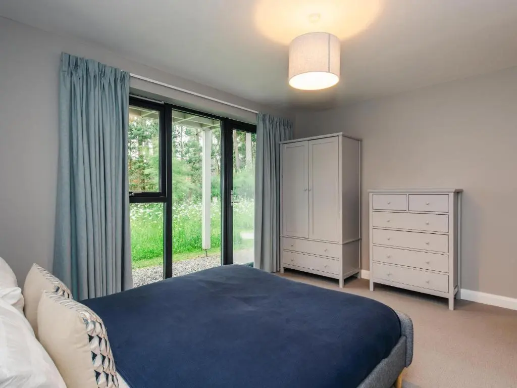 a bedroom with a bed and a large window at Wildcat Lodge in Kingussie