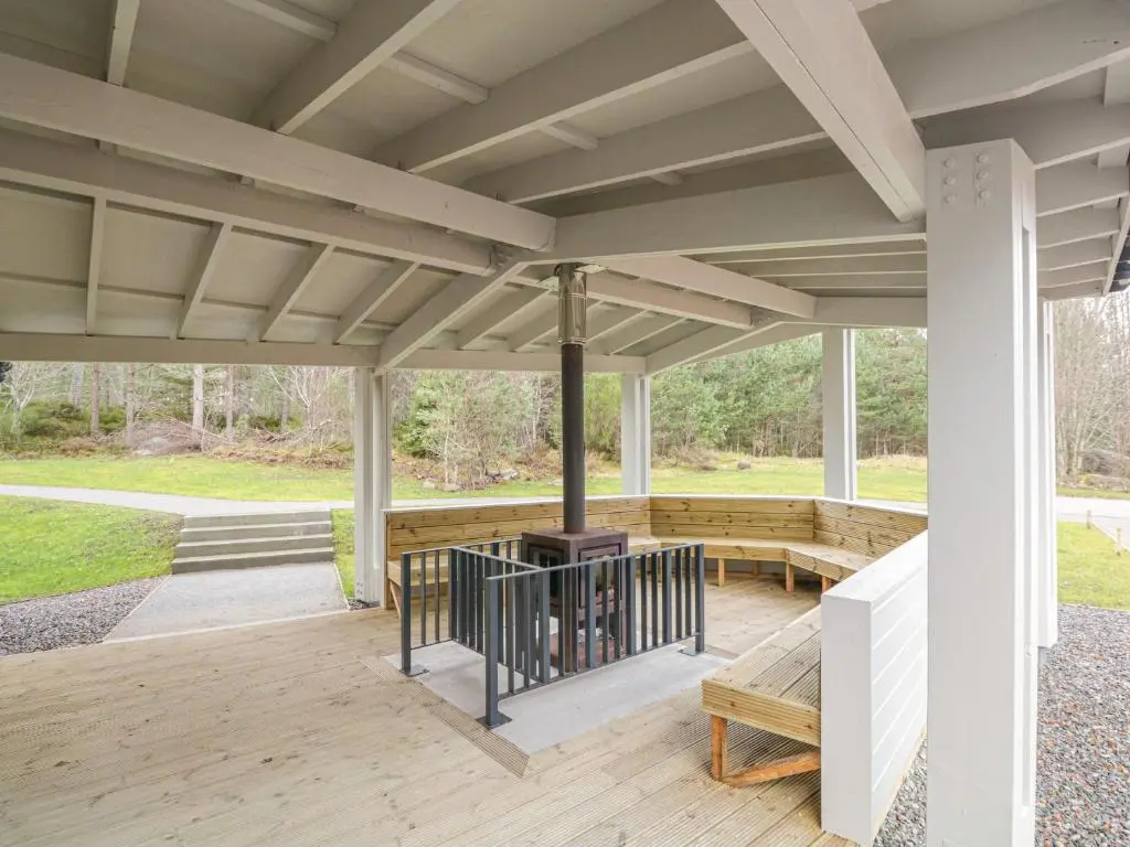 a pavilion with benches and a grill on a patio at Mountain Hare Apartment in Kingussie