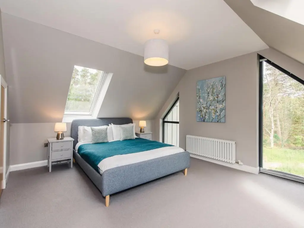 a bedroom with a bed and a large window at Osprey Apartment in Kingussie