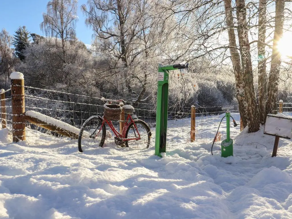 a bike parked next to a fence in the snow at Osprey Apartment in Kingussie
