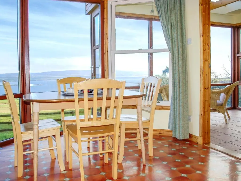 a dining room with a table and chairs and windows at Callachy Cottage - Uk7047 in Glenurguhart