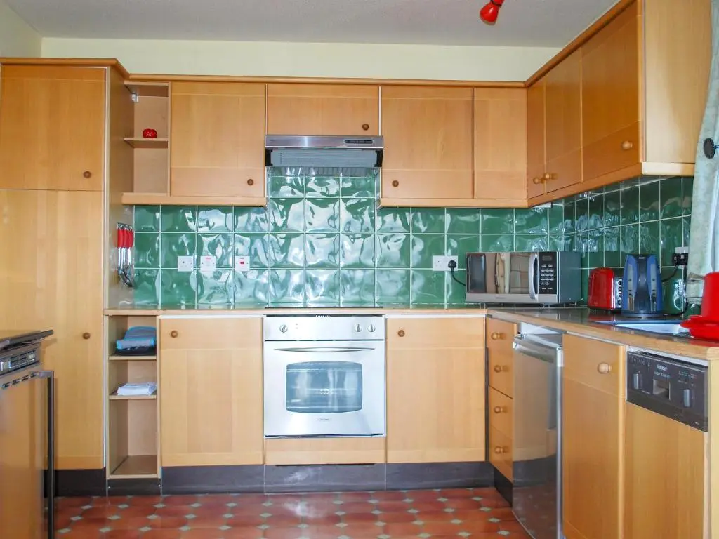 a kitchen with wooden cabinets and a stove top oven at Callachy Cottage - Uk7047 in Glenurguhart