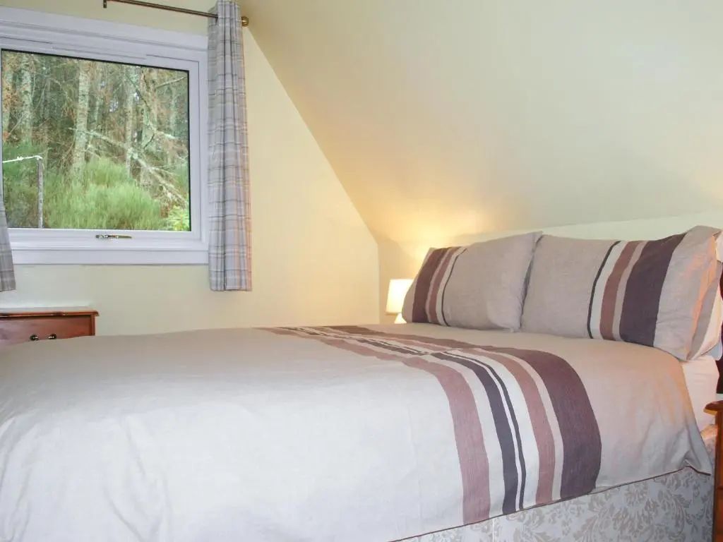a bedroom with a bed and a window at Heather Lodge in Glenurguhart