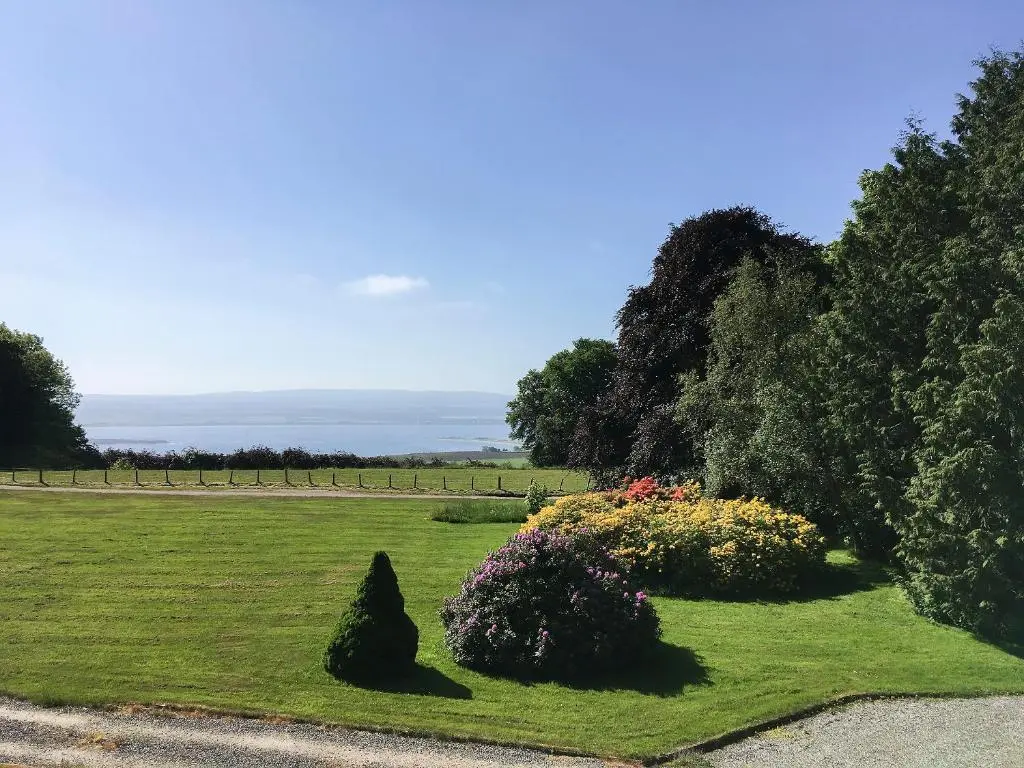 a garden with flowers and trees in a field at Heather Lodge in Glenurguhart