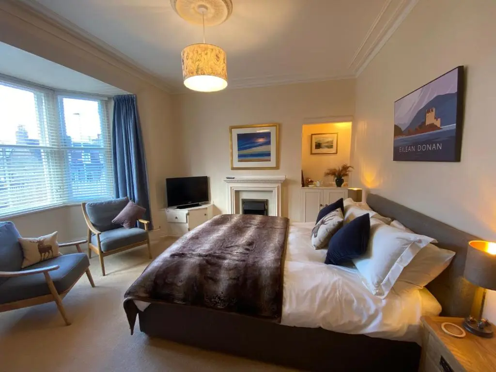 a bedroom with a large bed and a living room at Cranford Guest House in Braemar