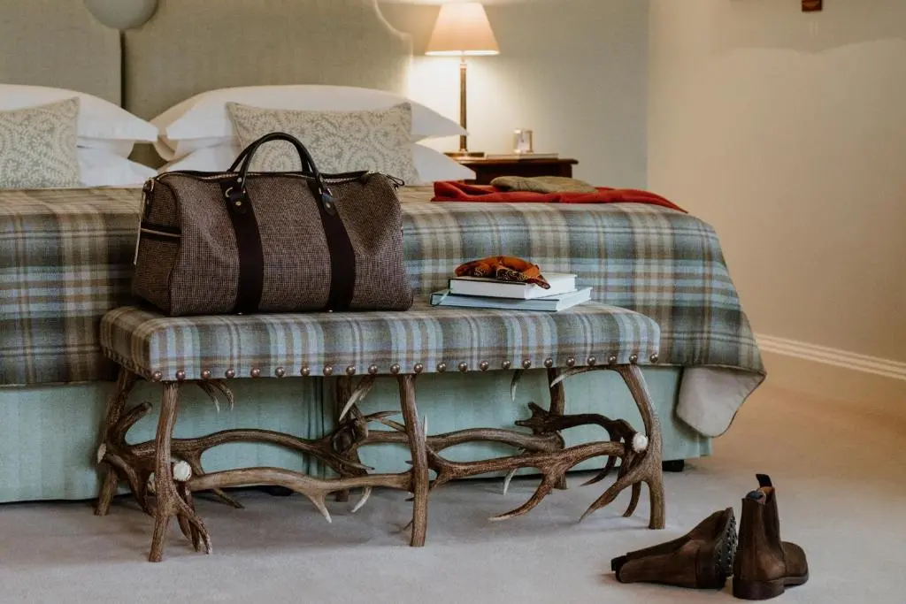 a bed with a bench with a purse and a book at Links House at Royal Dornoch in Dornoch
