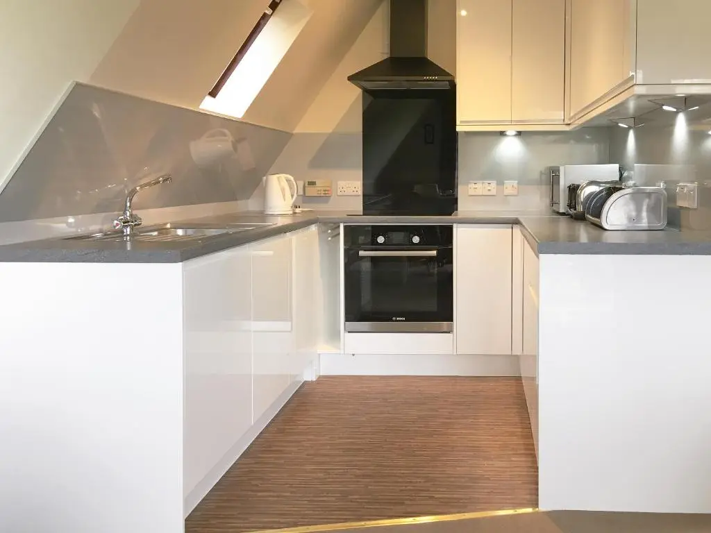 a kitchen with white cabinets and a black oven at Pine Lodge - Uk7049 in Glenurguhart