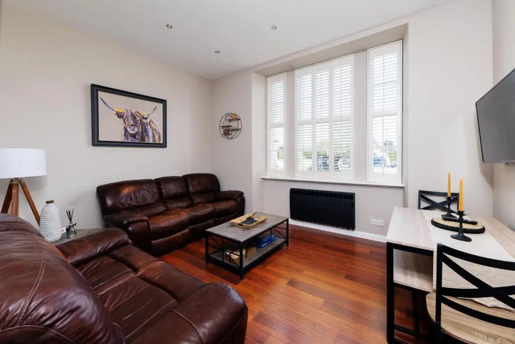 a living room with a leather couch and a television at Old Edinburgh Court in Inverness