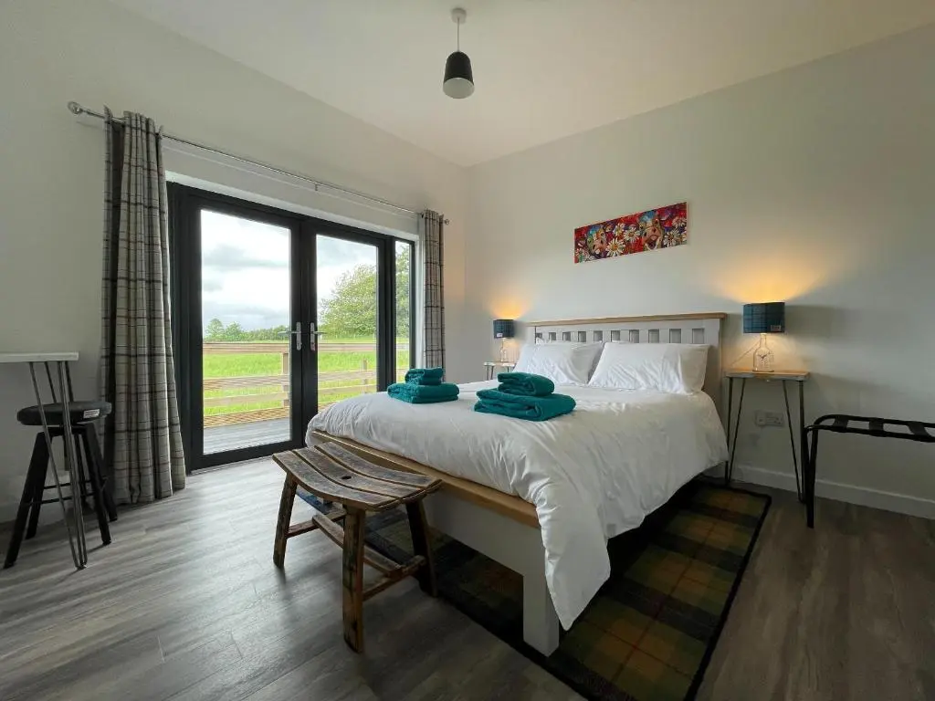 a bedroom with a large bed and a large window at Willow Lodge in Muir of Ord