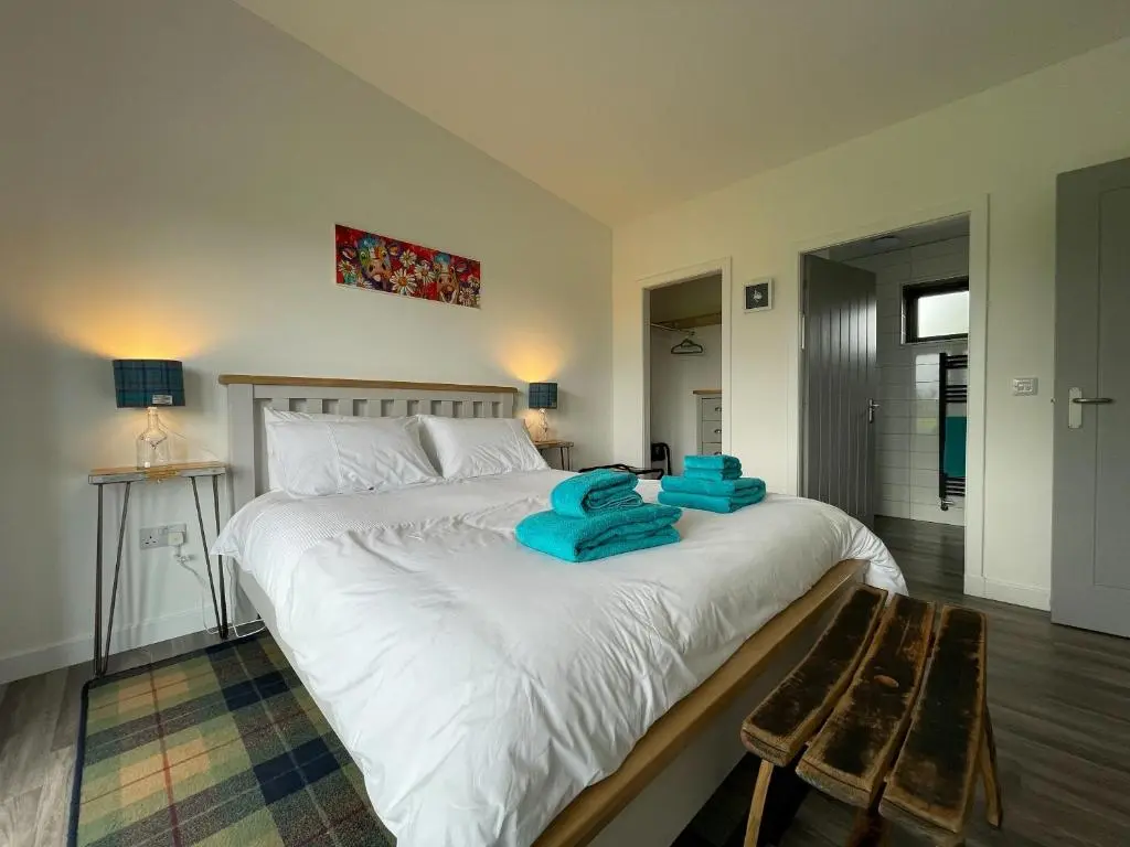 a bedroom with a large white bed with blue towels on it at Willow Lodge in Muir of Ord