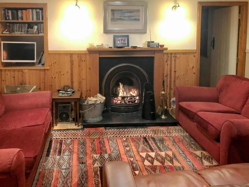 a living room with a fireplace with two red couches at Crofts in Badenyon