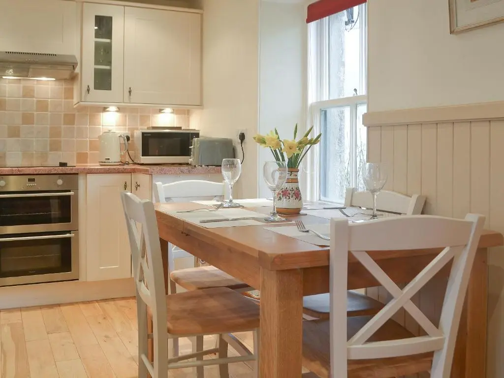 a kitchen with a wooden table and white chairs at Crofts in Badenyon