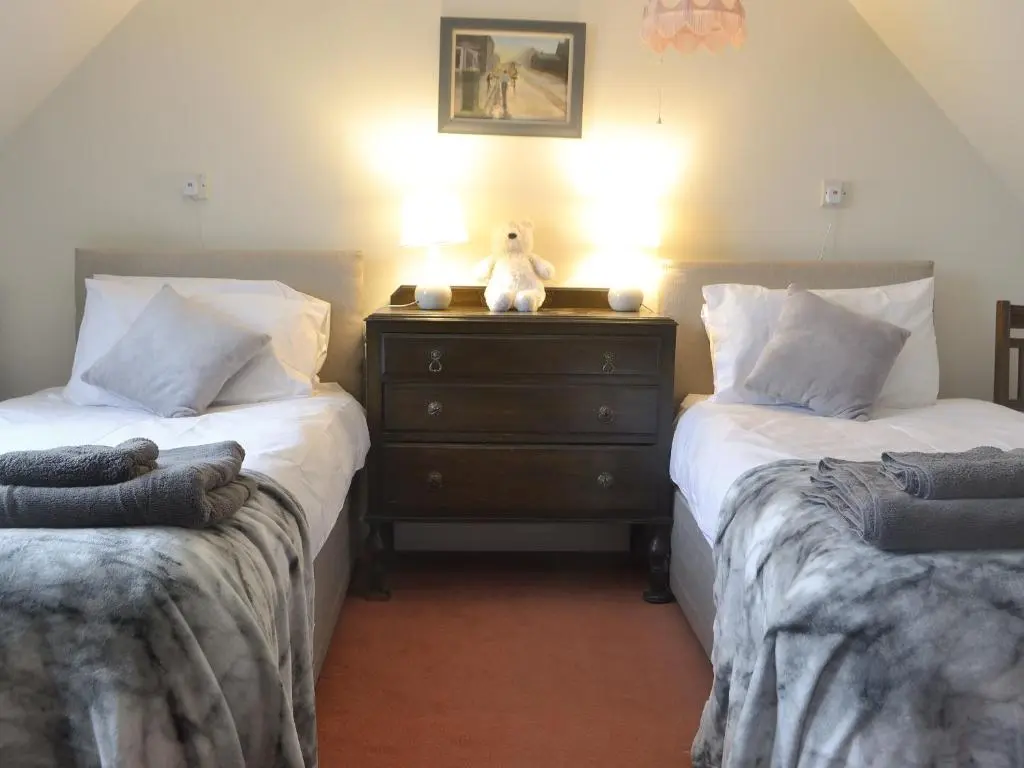 a bedroom with two beds and a stuffed animal on a dresser at Crofts in Badenyon