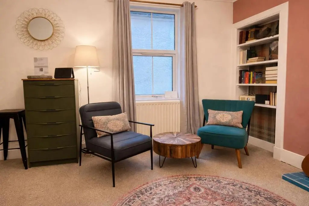 a living room with two chairs and a table and a window at Lamont Cottage in Inverness