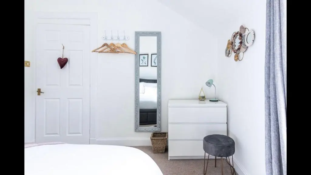 a bedroom with a white bed and a mirror at Lamont Cottage in Inverness